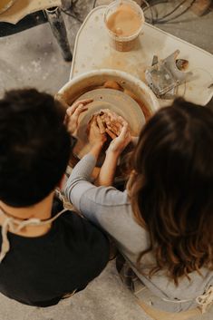 a man and woman are working on pottery