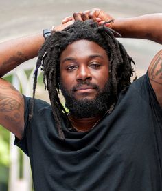 a man with dreadlocks is holding his hair in the air and looking at the camera