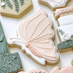 decorated cookies are arranged on a table with writing and flowers in the shape of butterfly wings