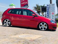 a red car parked in front of a sign