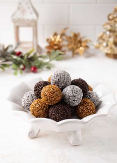 a white bowl filled with chocolate covered donuts on top of a counter next to christmas decorations