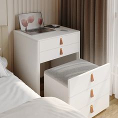 a laptop computer sitting on top of a white desk next to a bed with pillows