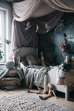 a child's bedroom with stuffed animals on the floor and curtains over the bed