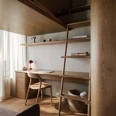 a room with a desk, chair and ladder in the corner next to a window