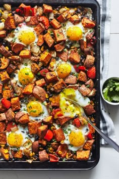 an egg and hash browns casserole on a baking sheet with a bowl of greens