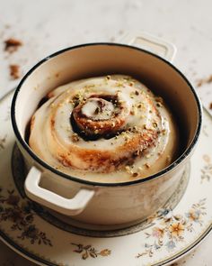 a cinnamon roll sitting in a pot on top of a plate