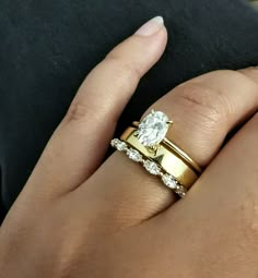 a woman's hand with two wedding rings on her left and the other hand holding an engagement ring