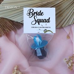 there is a small blue flower on top of the pink fabric and it says bride squad