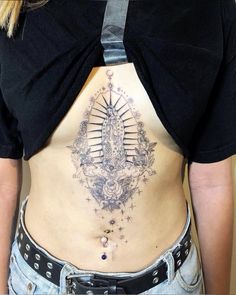 a woman's lower back tattoo with an image of the virgin mary on it