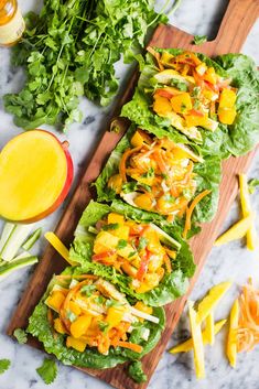 lettuce and cheese salad on a wooden cutting board next to sliced mangoes