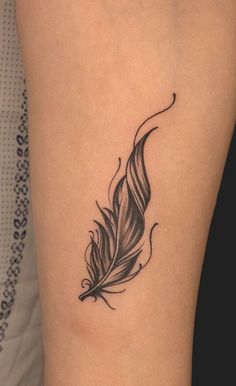 a black and white feather tattoo on the leg