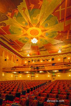 an empty auditorium with rows of seats and a ceiling painted in gold, red, and blue