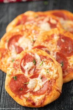 two pepperoni pizzas sitting on top of a wooden table