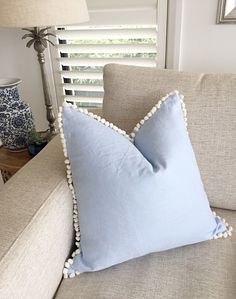 a light blue pillow with pom - poms on it sitting on a couch