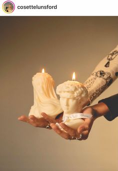 a person holding two candles in their hands