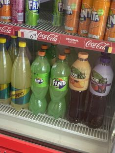 many different types of sodas are on display in a cooler, and one is empty