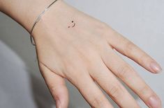 a woman's hand with a small smiley face tattoo on the middle of her wrist