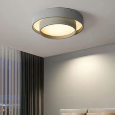 a bed room with a neatly made bed and a round light fixture above the headboard