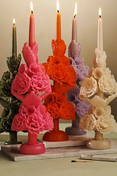 five candles with different colored flowers on them