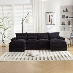 a black sectional sofa sitting on top of a wooden floor next to a white rug