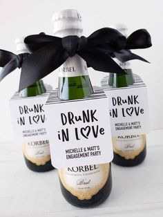 three bottles of wine with black ribbon tied around them and labels on the top for drink in love