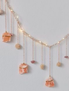 a gold chain with pink stones hanging from it's sides on a white wall