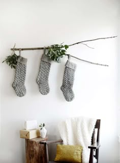 two stockings hanging from a tree branch in front of a white wall