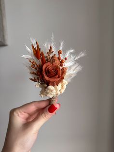 a person holding a flower in their hand with feathers and flowers on the top of it