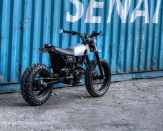 a motorcycle parked in front of a blue metal wall with the words sema on it