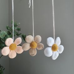 three crocheted flower ornaments hanging from strings