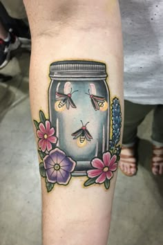 a person with a tattoo on their arm and the image of a jar filled with flowers