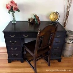 a desk with a chair, vase and flowers on it