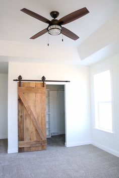 an empty room with a sliding door and a ceiling fan in the middle of it