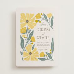 a wedding card with yellow flowers and green leaves on the front, printed in white paper