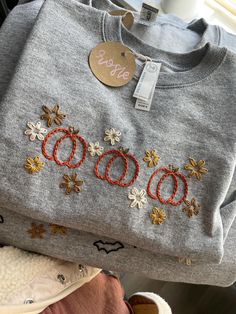 three sweaters with embroidered numbers and flowers on them