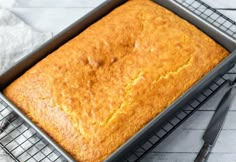 a loaf of bread sitting on top of a cooling rack next to a knife and fork