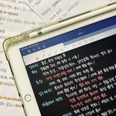 an open laptop computer sitting on top of a pile of paper with writing on it