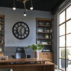 a large clock mounted to the side of a wall above a desk in an office