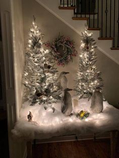 two snow covered trees with lights on them in front of a banister and stairs