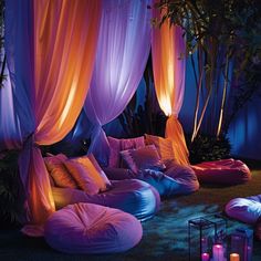 an outdoor lounge area with purple and orange drapes, bean bag chairs, and lit candles