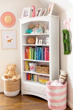 a white book shelf with books and toys on it in a child's room