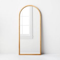 an arched wooden mirror against a white wall