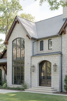 a white brick house with two large windows and an arched door on the front porch