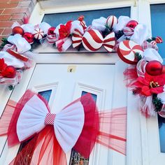 a door decorated for christmas with red and white bows, ornaments and candy canes