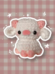 a crocheted stuffed animal sitting on top of a pink and white checkered table cloth