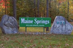 two large rocks sitting in front of a sign for maine springs