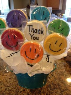 a bunch of smiley face cookies sitting on top of a blue cup filled with candy