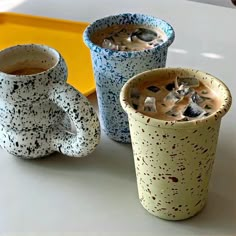 three ceramic cups are sitting on a table