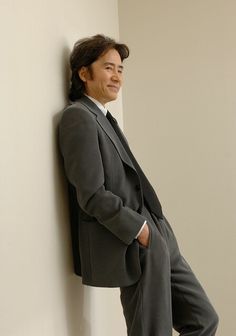 a man in a suit leaning against a wall