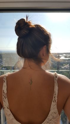 a woman with her back to the camera, looking out at the ocean and buildings